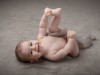 Immagine di bebé sdraiato che si afferra i piedini durante servizio fotografico in studio di Bebé
